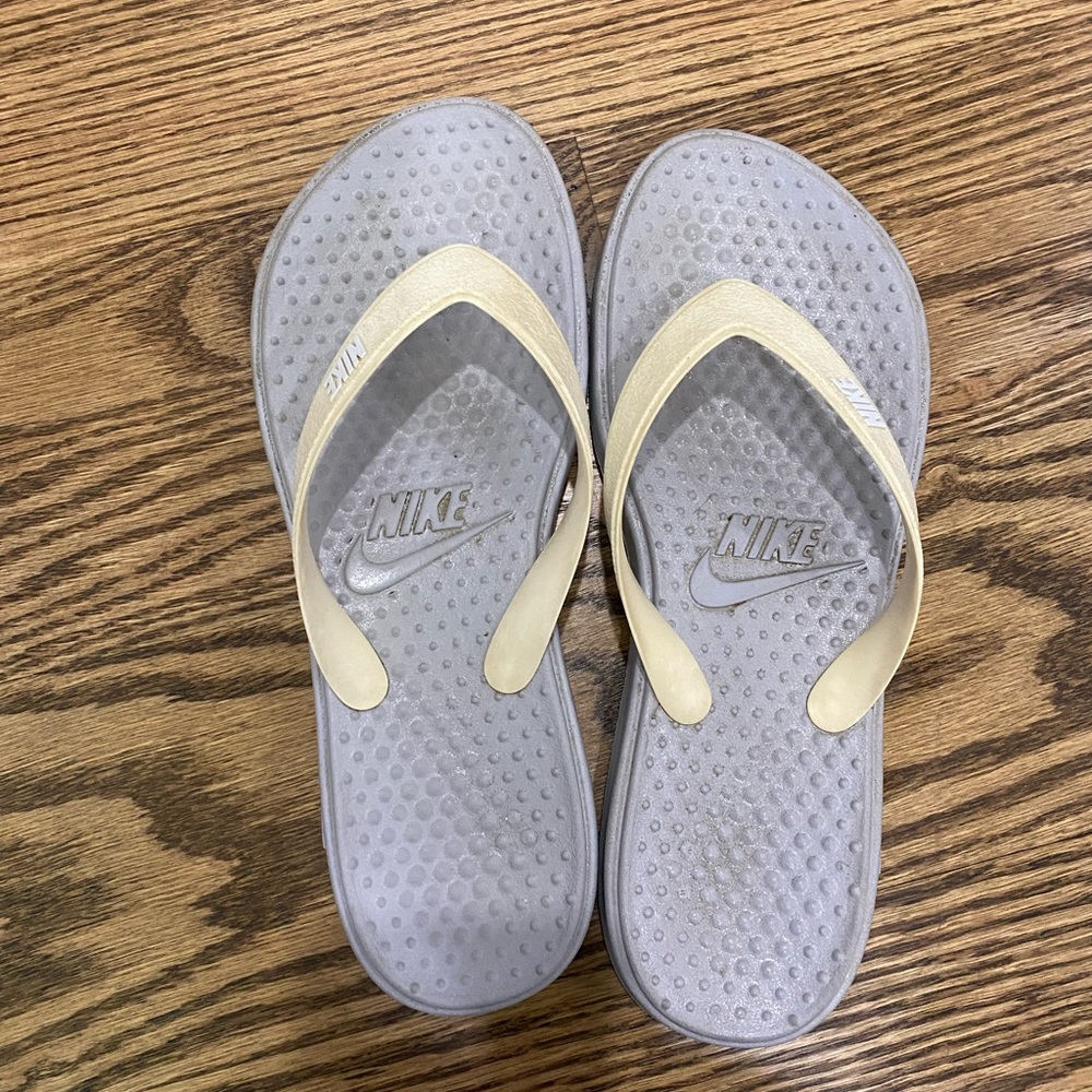 Grey Nike flip flops embellished by Nike monogram and logo on thong